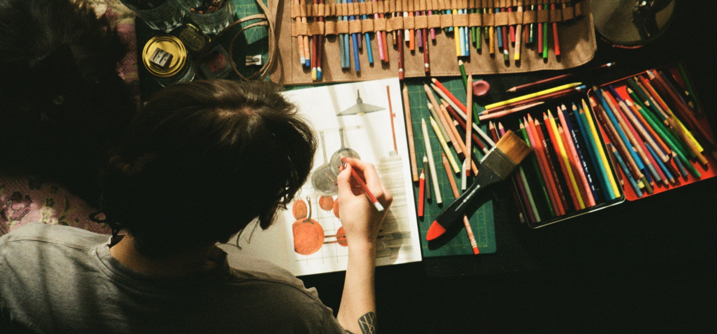 Kateryna at her studio desk, drawing with colored pencils