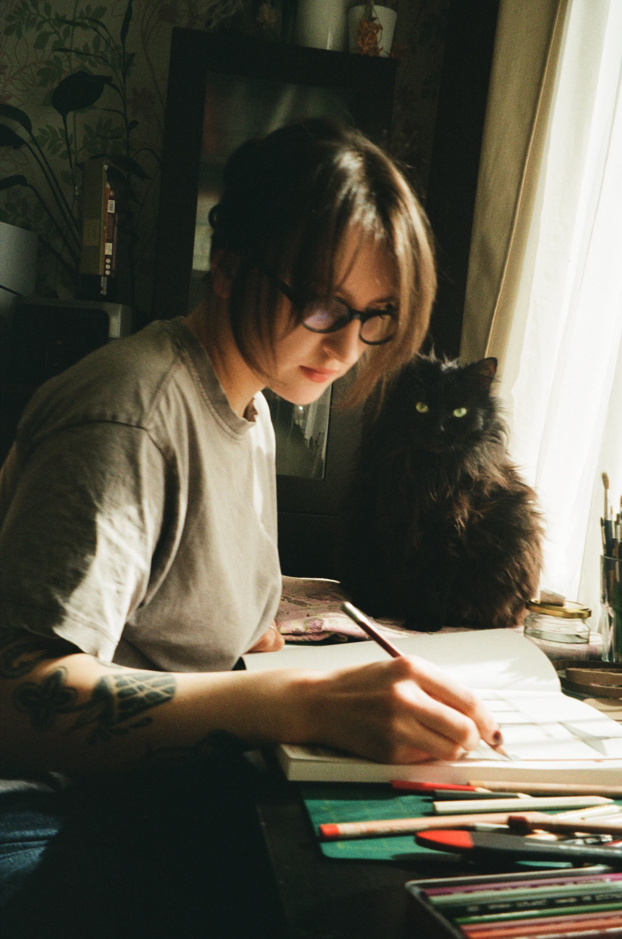 Kateryna drawing at her desk, with her cat